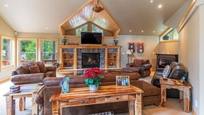 A spacious living room with a stone fireplace, leather sofas, and a wooden coffee table. - 4BR Incline Village Home | Hot Tub, Game Room (Incline Village)