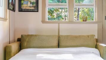 Une chambre à coucher avec un lit, deux fenêtres et une porte.