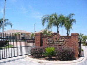 Une porte d’entrée en briques avec une enseigne indiquant « Sun Lake Condominiums ».