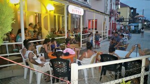 An outdoor seating area of a hotel with tables and chairs, a sign reading "HOTEL RITSA", and a fence surrounding the area. - Hotel Ritsa (Ureki)