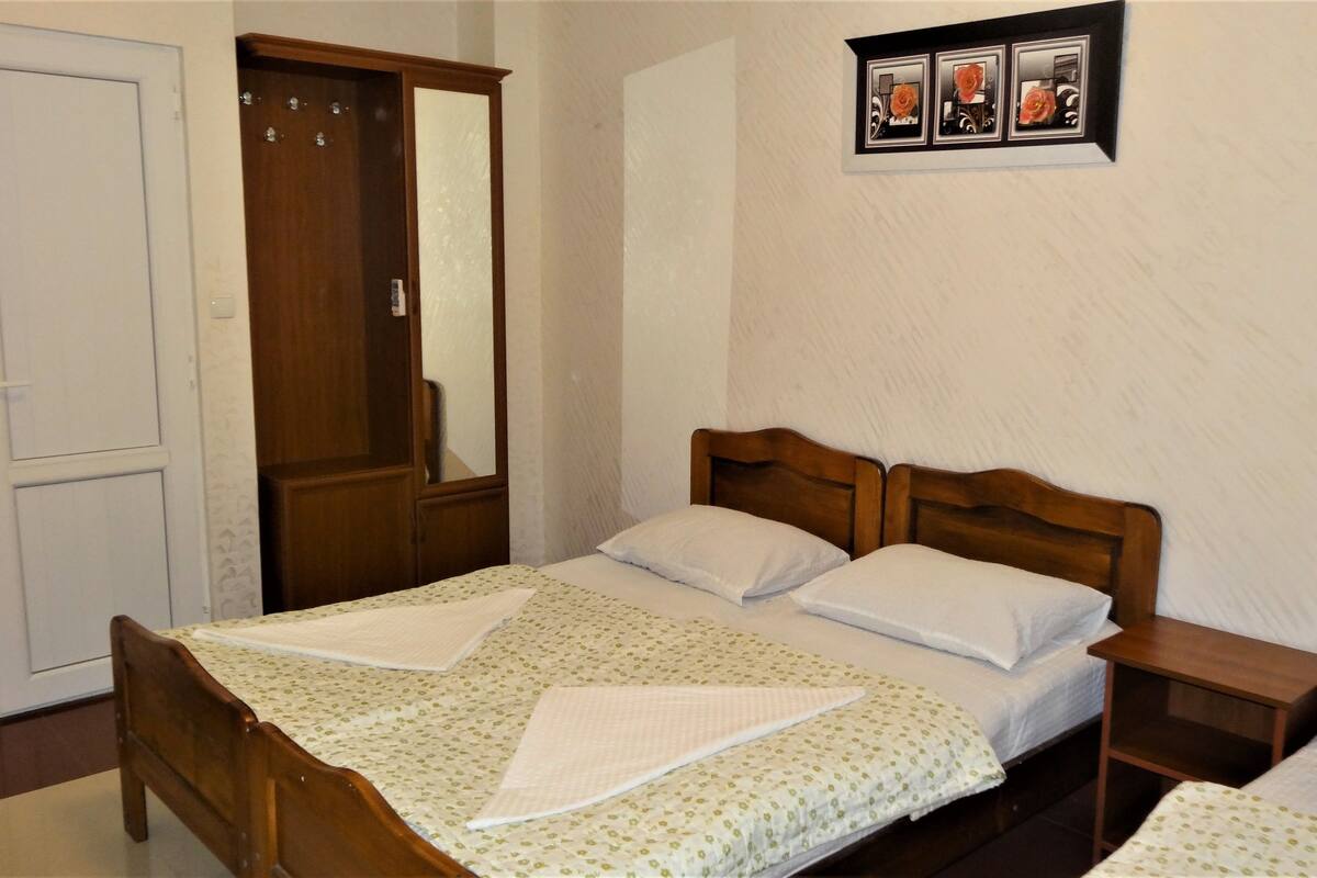 A bedroom with a wooden bed, two bedside tables, a wardrobe, and a mirror.