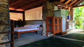 A room with a bed, a wooden cabinet, and a stone wall.