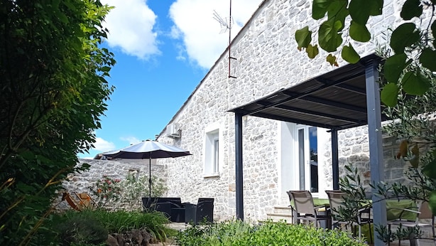 A stone building with a covered patio area, outdoor seating, and a gravel path.