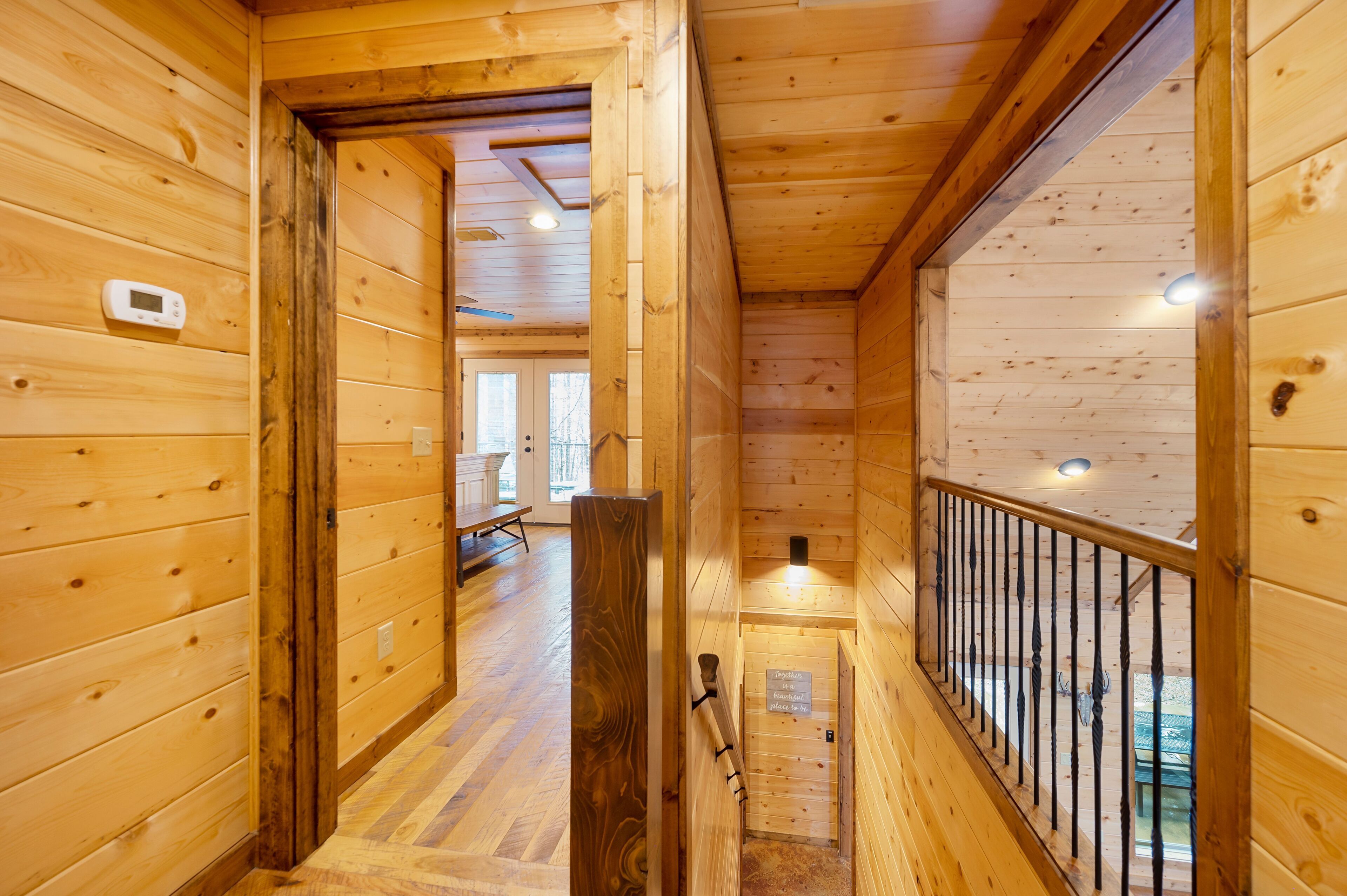 A wooden interior hallway with a bench, a thermostat, and a sign on the wall.