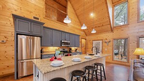 Une cuisine spacieuse dotée d’un grand îlot central, d’appareils électroménagers en acier inoxydable et d’un intérieur en bois.