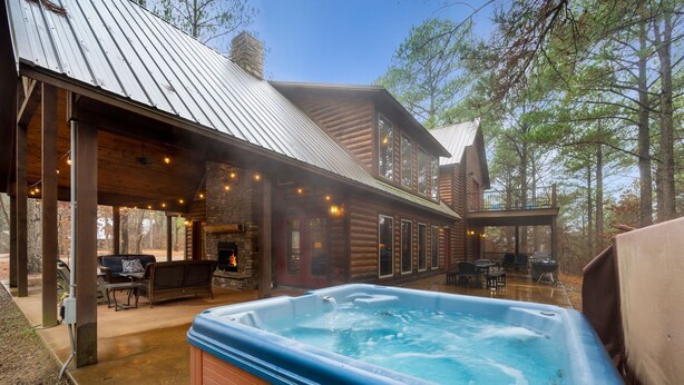 Une cabane en rondins avec un jacuzzi, un espace salon extérieur et une cheminée.