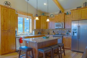 A kitchen with wooden cabinets, a stainless steel refrigerator, a microwave, and a granite countertop.