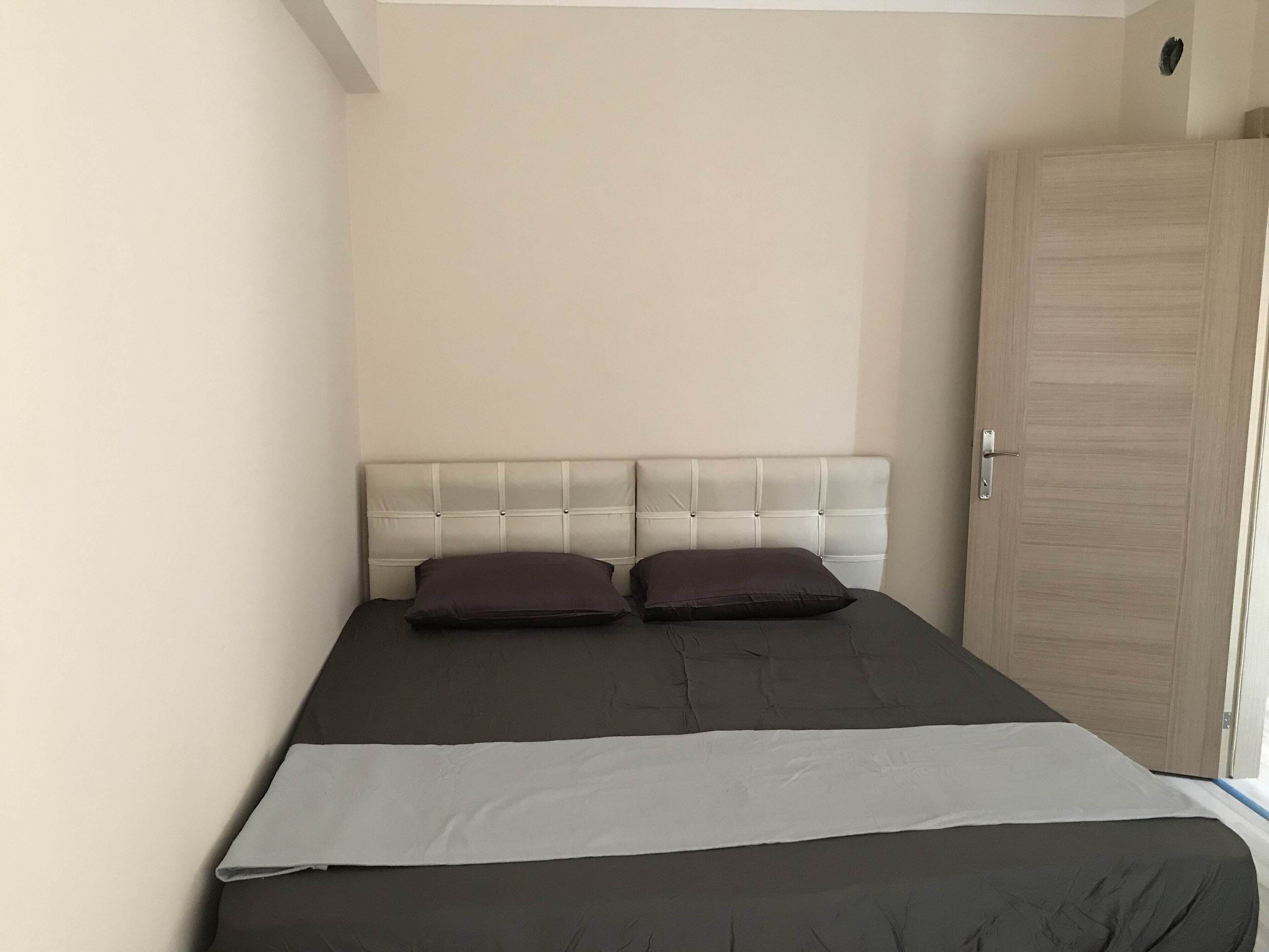 Un dormitorio con una cama, dos almohadas, un armario de madera y una ventana.