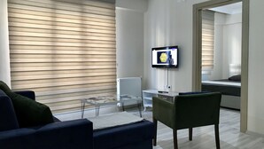 A modern living room with a sofa, a glass coffee table, and a television mounted on the wall. - Edirne Apart (Edirne)
