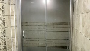 A bathroom with a glass-enclosed shower, a toilet, and tiled walls. - Edirne Apart (Edirne)