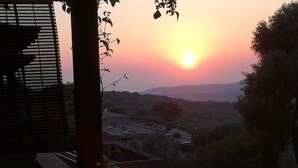 A sunset view from a balcony with a view of the surrounding landscape, including trees and distant hills. - Lucianasit, in the heart of the Emerald Coast and its wonderful beaches. (Olbia)