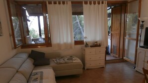 A cozy living room with a sofa, a small ottoman, a white dresser, and a television. - Lucianasit, in the heart of the Emerald Coast and its wonderful beaches. (Olbia)