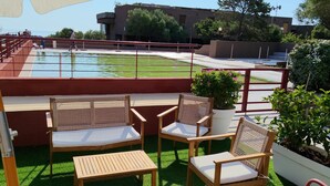 An outdoor seating area with chairs and tables, a pool, and a building in the background. - Lucianasit, in the heart of the Emerald Coast and its wonderful beaches. (Olbia)