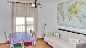 Ein Zimmer mit Esstisch, Stühlen, einer Couch, einer Karte an der Wand und einer Chandelüstere.
