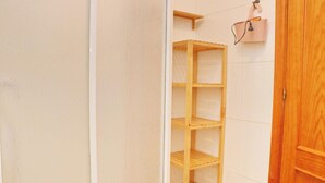Ein Badezimmer mit einer weißen Fliesenwand, einer Holztür und einem Holzregal.