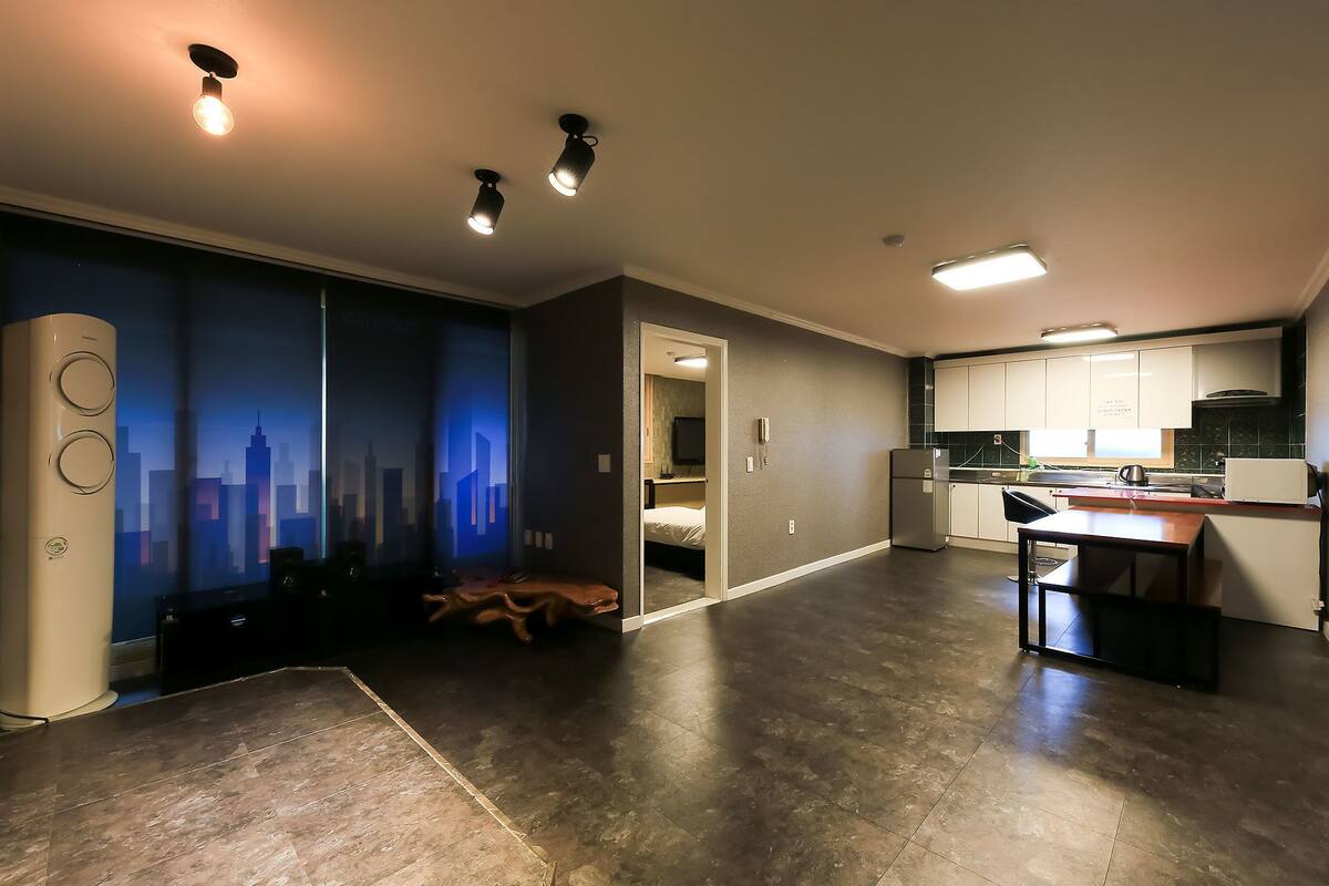A modern kitchen with dark flooring, recessed lighting, and a cityscape mural on the wall.