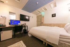 Habitación de hotel con cama, escritorio, ordenador y televisor.