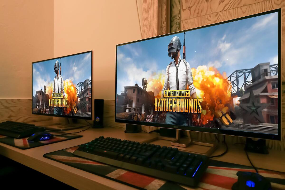 Two monitors displaying PUBG Mobile on a desk with a keyboard and mouse.