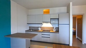 A compact kitchen with a built-in oven, a sink, and a countertop with a kettle. - Appartamento 105 Benaco (Tignale)