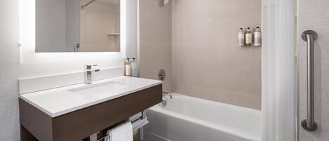 A modern bathroom with a white sink, dark wooden vanity, and a standalone bathtub.