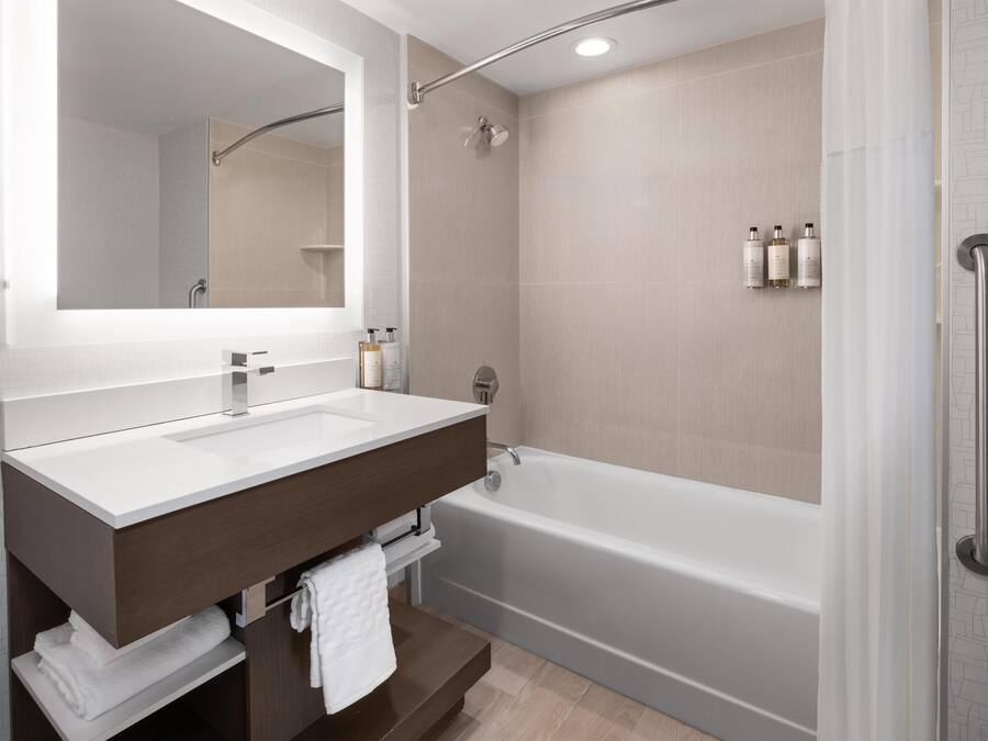 A modern bathroom with a white sink, dark wooden vanity, and a standalone bathtub.