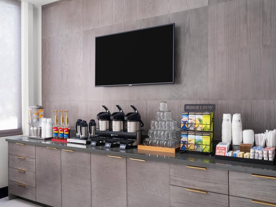 Una cocina moderna con televisor de pantalla plana, cafeteras y una estación de bebidas.