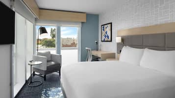 Una habitación de hotel con una cama grande, un escritorio, una silla y un televisor.