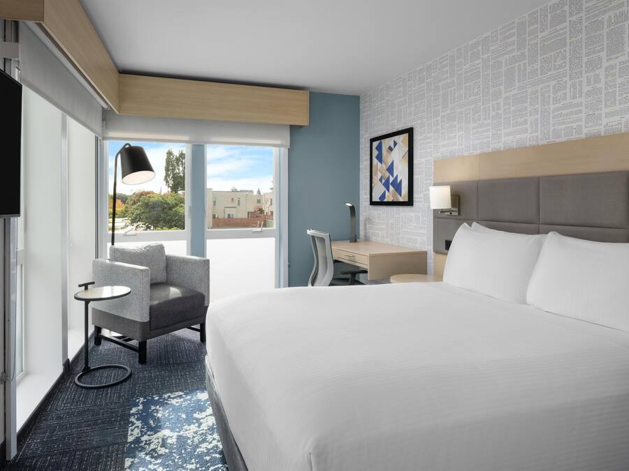 Una habitación de hotel con una cama grande, un escritorio, una silla y un televisor.