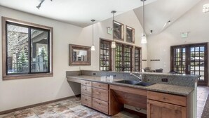 A spacious kitchen with a large island, multiple windows, and a high ceiling.