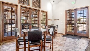A restaurant with multiple wooden-framed windows, a tiled floor, and several tables with chairs.