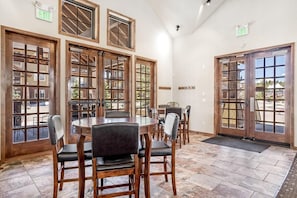 Un restaurante con amplios ventanales de madera, piso de baldosas y varias mesas con sillas.