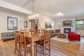 Un salón amplio con una mesa de comedor de madera, un sofá rojo, chimenea y televisor montado en la pared.