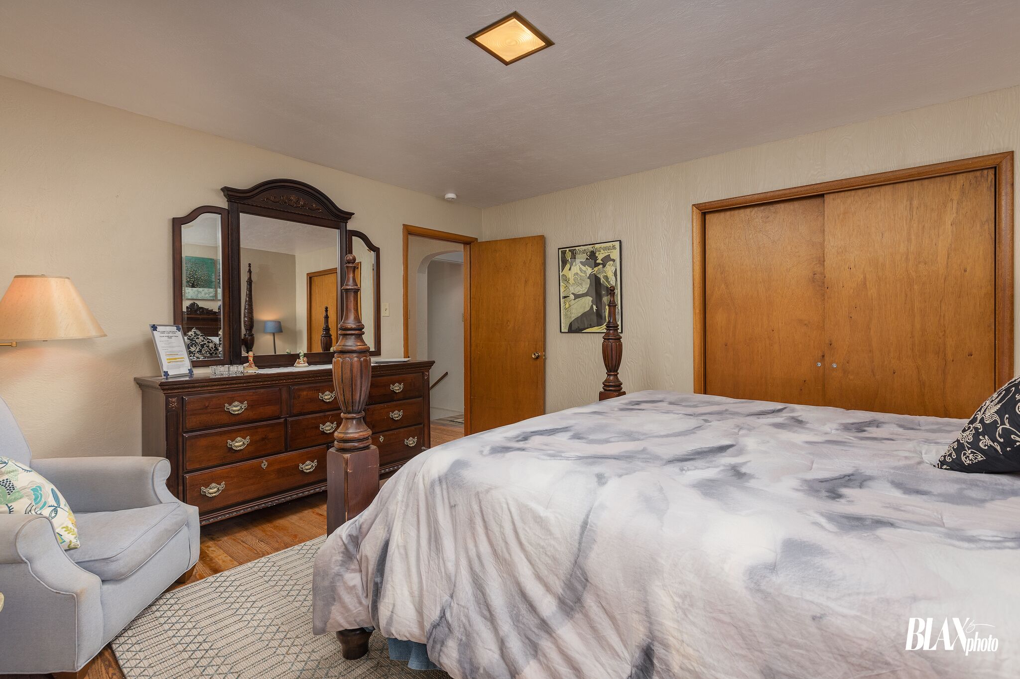 Une chambre à coucher comprenant un lit, une commode, un miroir et une porte donnant sur une autre pièce.