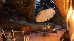 Une terrasse extérieure équipée d’un barbecue, de sièges et d’une table avec un auvent.