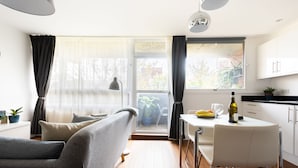 A modern kitchen with a dining table, chairs, and a window with curtains. - Smart Modern Studio in Pimlico with Garden Views (London)