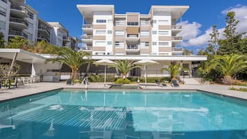 Een buitenzwembad, parasols bij het zwembad en ligstoelen