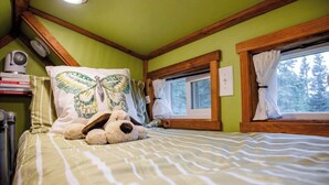 A cozy room with a bed, a window, a wall-mounted heater, and a butterfly pillow. - Escape. Just You. Peace, Animals & Nature (Longview)