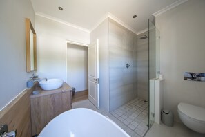 A modern bathroom with a freestanding bathtub, a glass-enclosed shower, and a toilet.