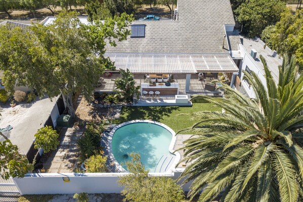 A residential property with a swimming pool, a covered patio, and a well-maintained lawn.