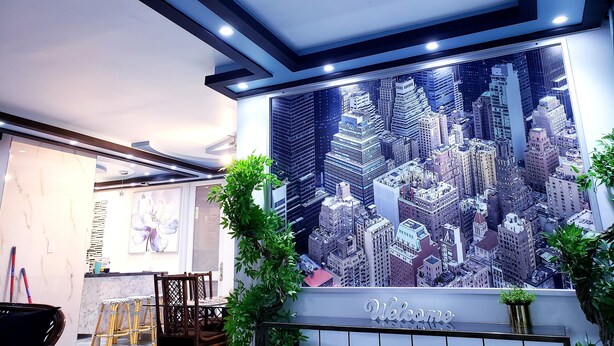 Un intérieur moderne agrémenté d’une fresque représentant un paysage urbain, d’un comptoir d’accueil et d’une pancarte « Bienvenue ».