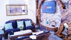Un salon moderne avec un canapé, une table basse et un téléviseur à écran plat fixé à un mur en bois.
