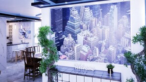 Un espace d’accueil agrémenté d’une fresque représentant un paysage urbain, d’une pancarte « Bienvenue » et d’un coin salon avec des chaises et une table.