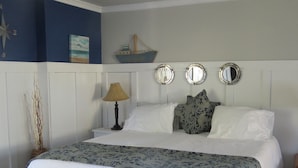 Un lit bien fait, avec une couvre-lit à motifs, deux oreillers et une lampe de chevet.