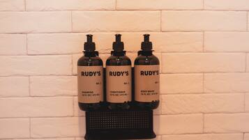 Three bottles of Rudy's products on a wall-mounted dispenser.
