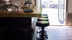 A bar area with a wooden counter, stools, and hanging pendant lights. - Stonehill's Farmhouse (Accord)