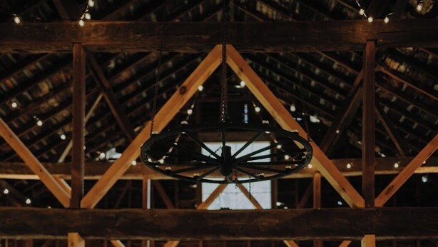 A rustic hall with wooden beams, long tables set for dining, and a high ceiling with exposed beams. - Stonehill's Farmhouse (Accord)