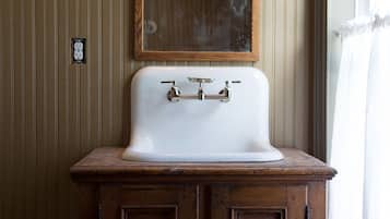 A bathroom with a wooden vanity, a white sink, and a mirror above it.