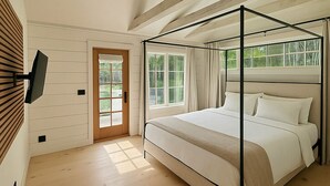 A bedroom with a four-poster bed, a television mounted on the wall, and a large window with curtains. - Stonehill's Farmhouse (Accord)