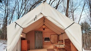 A tent with a wooden interior, including a sofa, a dresser, and a fireplace. - Stonehill's Farmhouse (Accord)