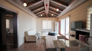 A modern interior with a wooden ceiling, a sofa, a coffee table, and a television. - Sunset in Garden (Seogwipo)